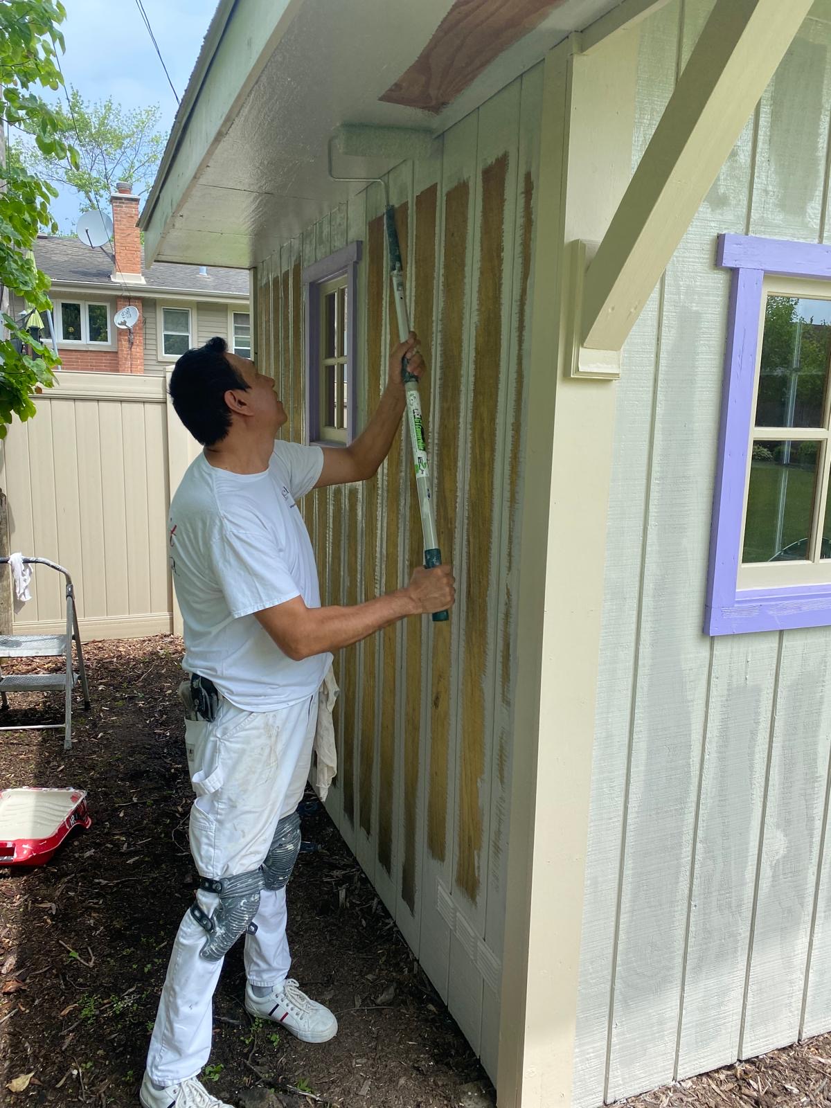 Painter working on shed exterior